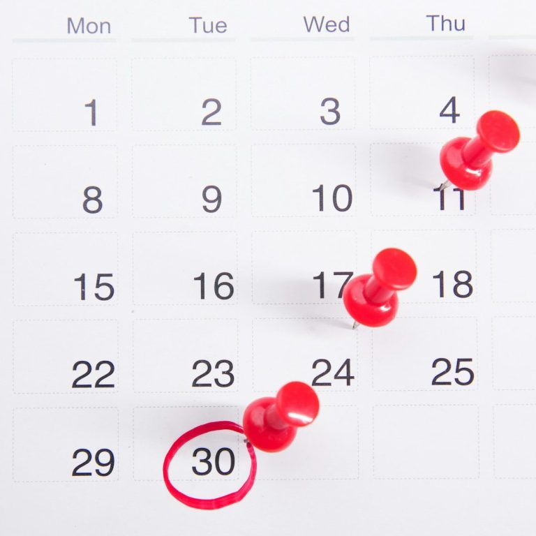 Junge Frau in einem Feld voller Blumen, die eine Blume in der Hand hält und lächelt.