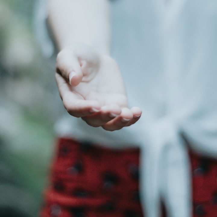 Eine ausgestreckte Hand in einem natürlichen Hintergrund.
