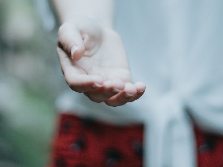 Offene Hand mit leicht gespreizten Fingern, in unscharfem Hintergrund.