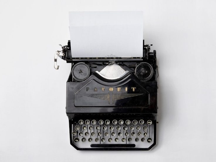 Schreibmaschine mit leerem Blatt auf weißem Hintergrund.