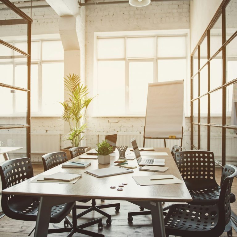Konferenzraum mit Holztisch, Bürostühlen und Panoramafenster mit Stadtblick.