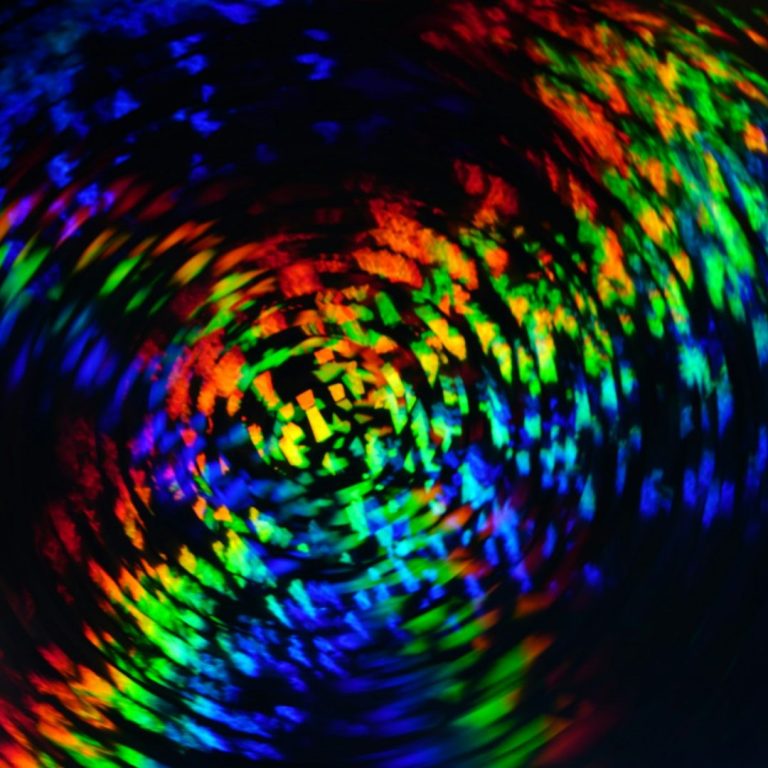 Farbenfrohe, spiralförmige Lichtmuster auf dunklem Hintergrund.